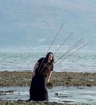Woman standing on a beach holding fishing poles