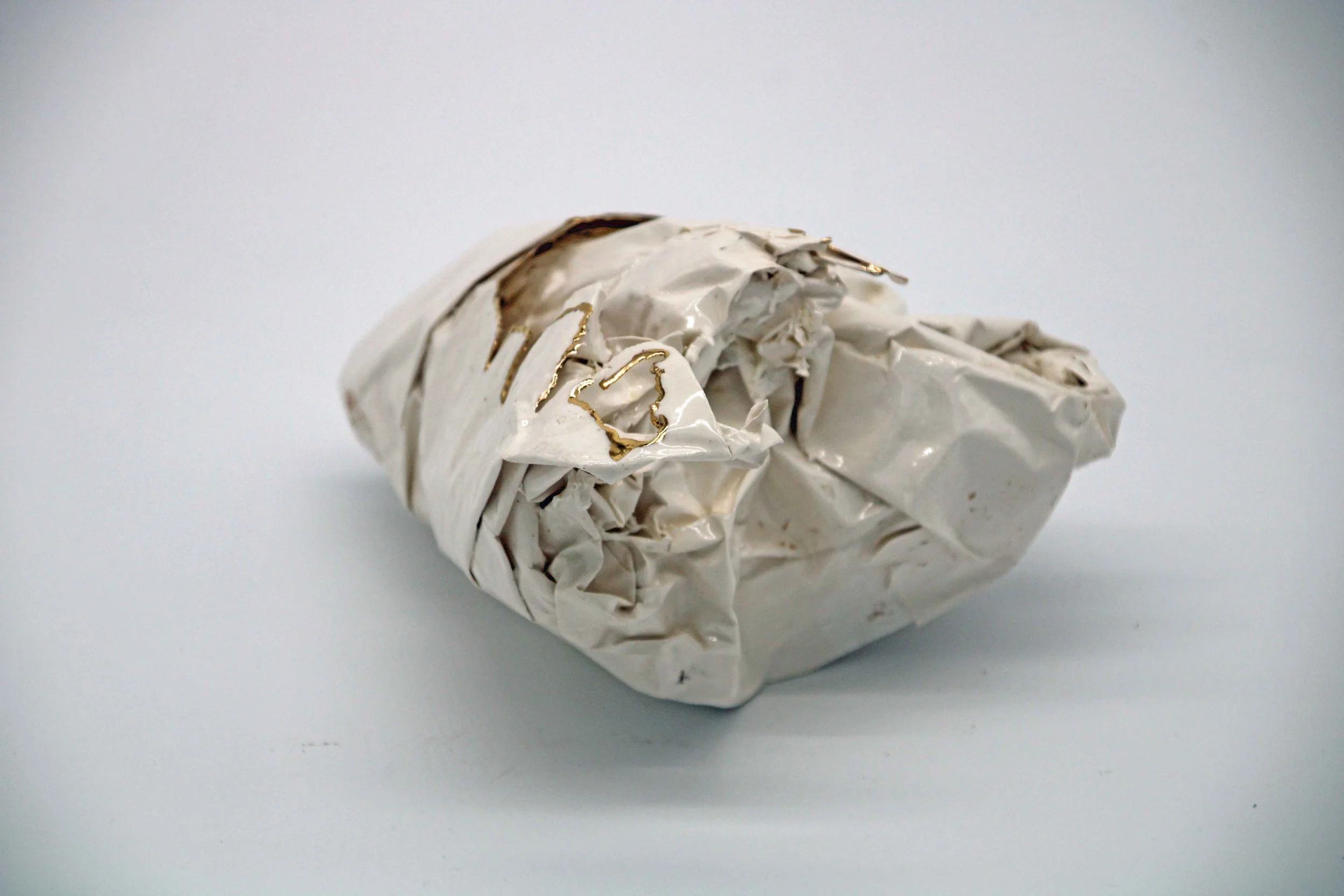 white ceramic piece that looks like scrunched paper with gold on some edges