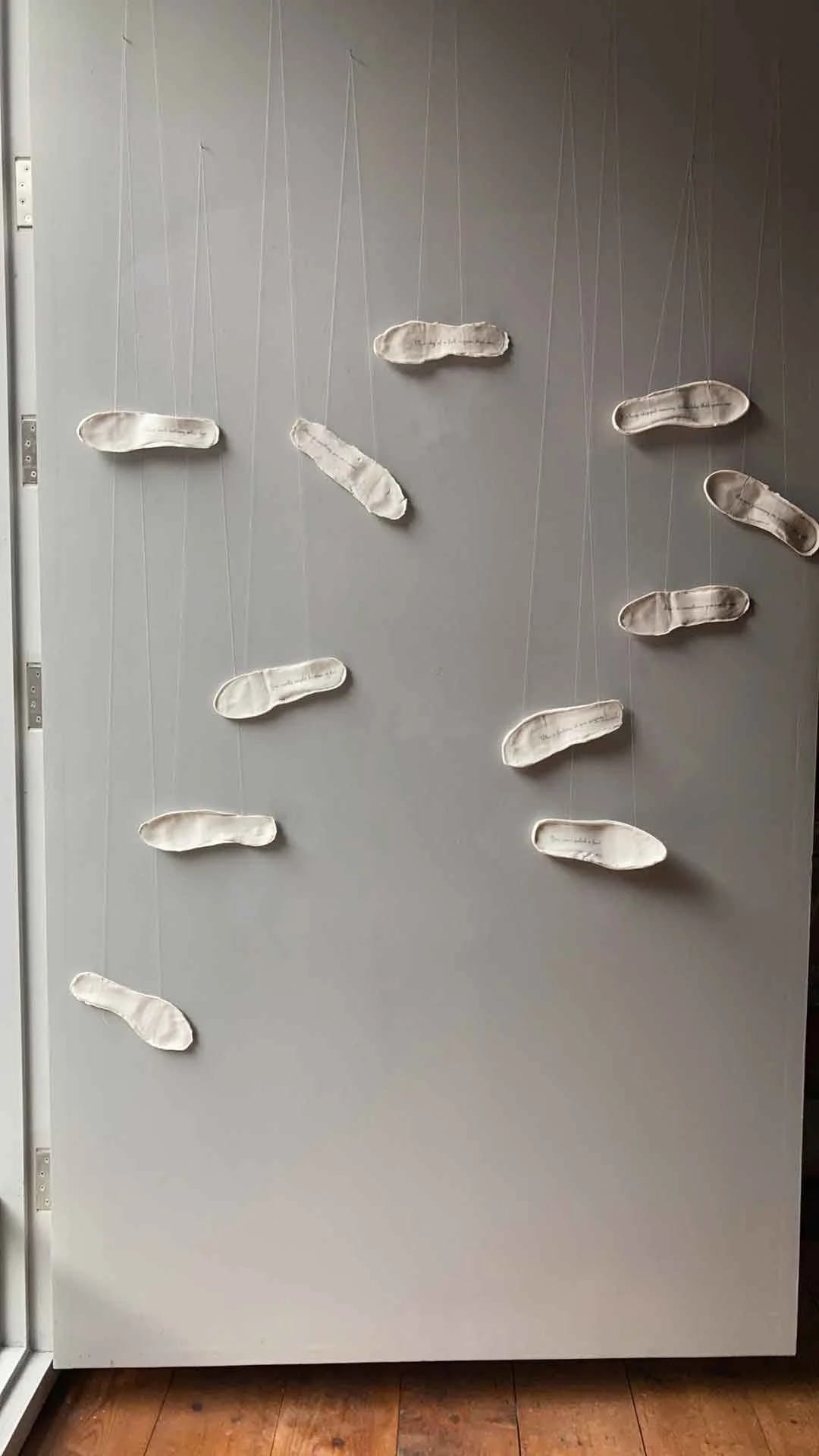 A display on a gray door with paper footprints hanging from strings, resembling a landing pattern.