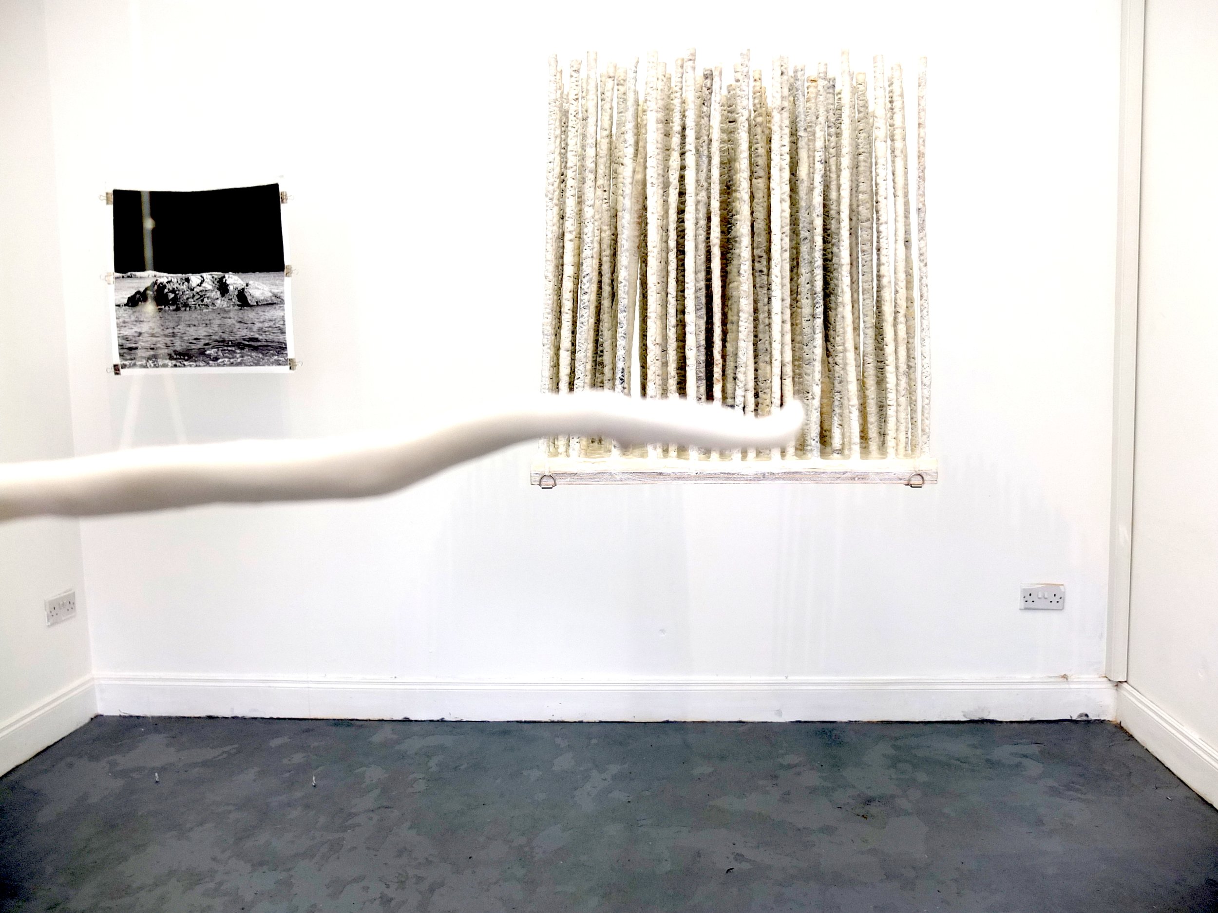 A room with white walls and white rood like artwork hanging from the ceiling