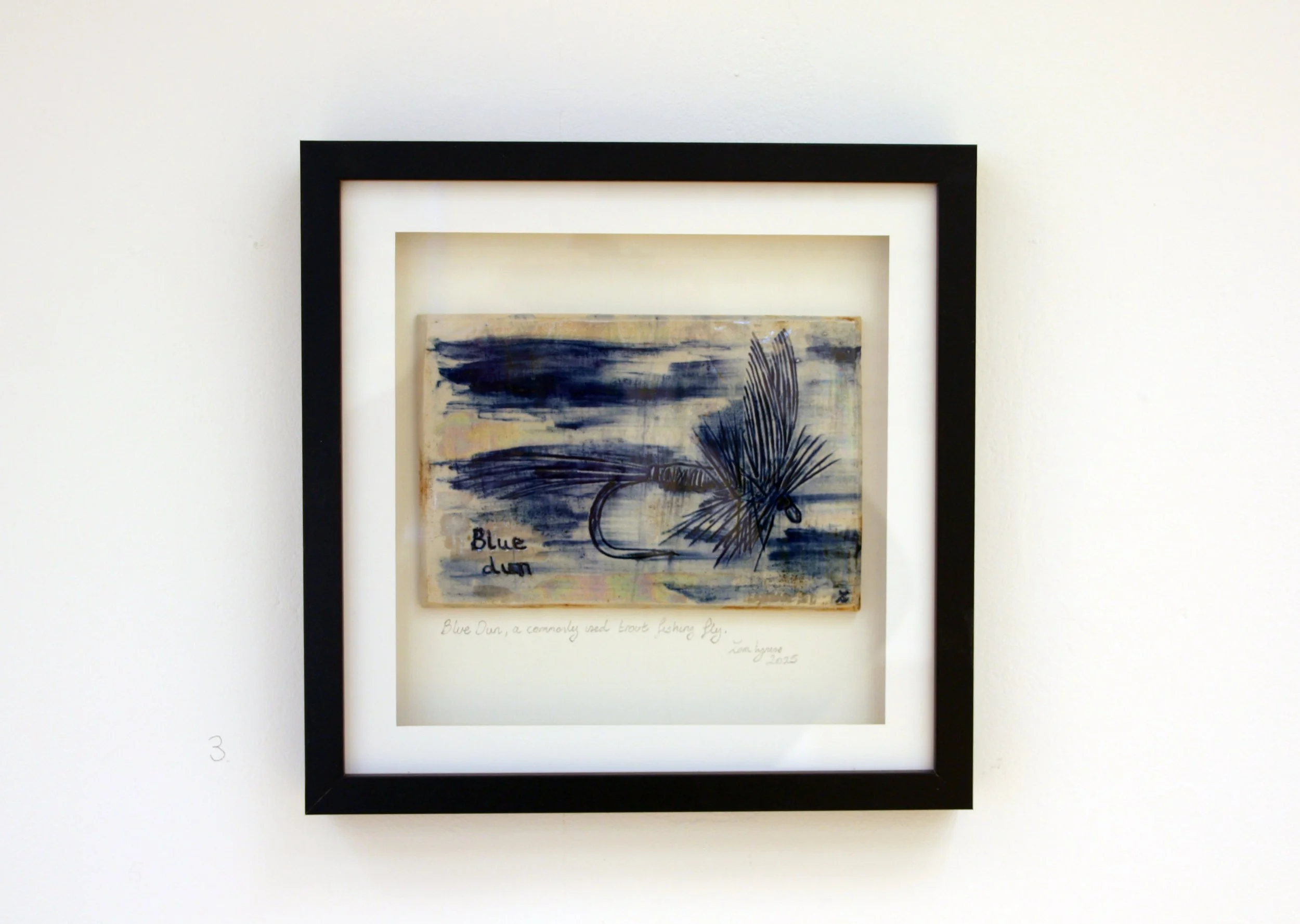 An art piece titled 'Blue Dane' featuring abstract navy blue brushstrokes and a large feather sketch on a beige background, framed in black and white matte.