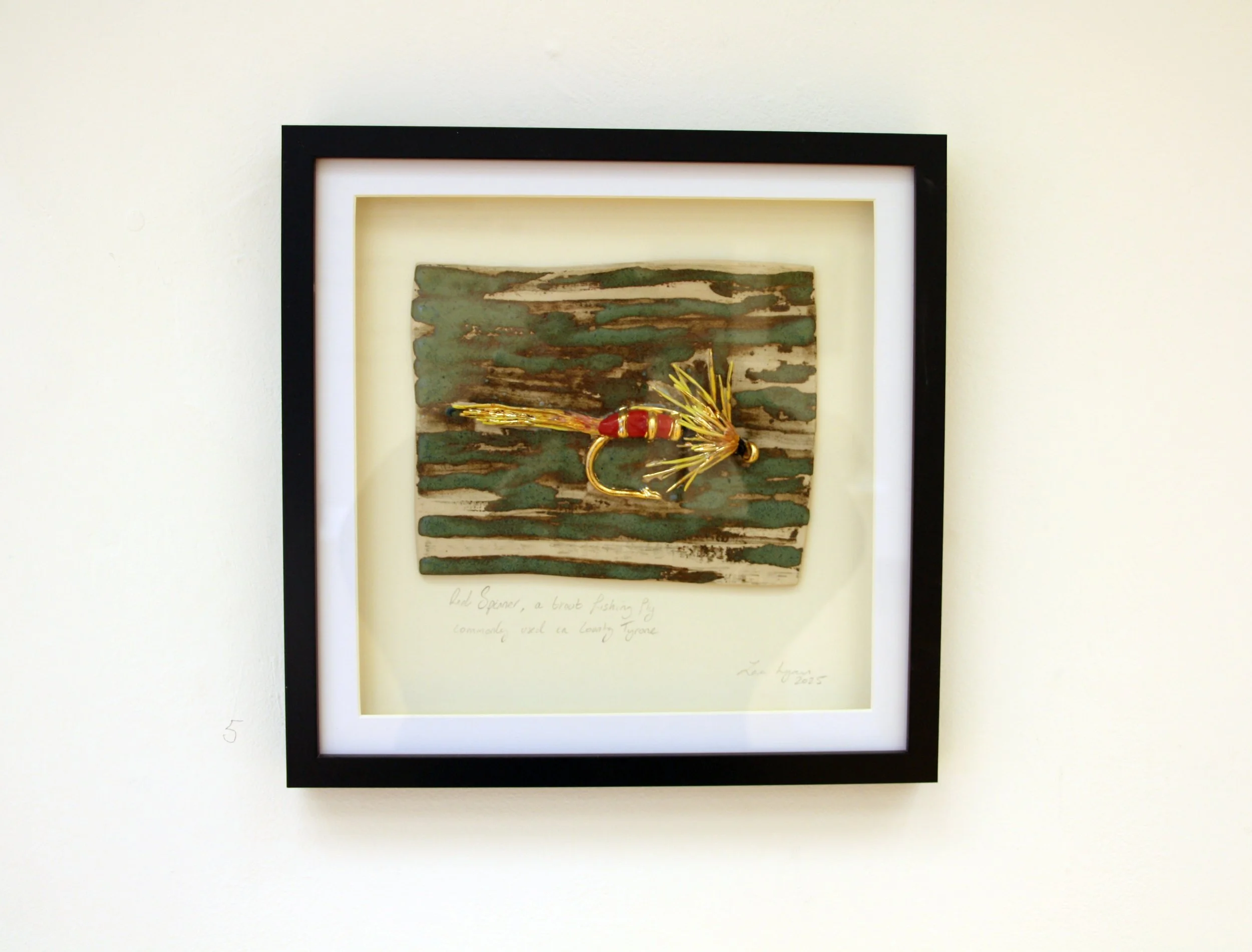 Framed mixed media artwork featuring a piece of driftwood and a gold and red insect sculpture, with handwritten notes below.