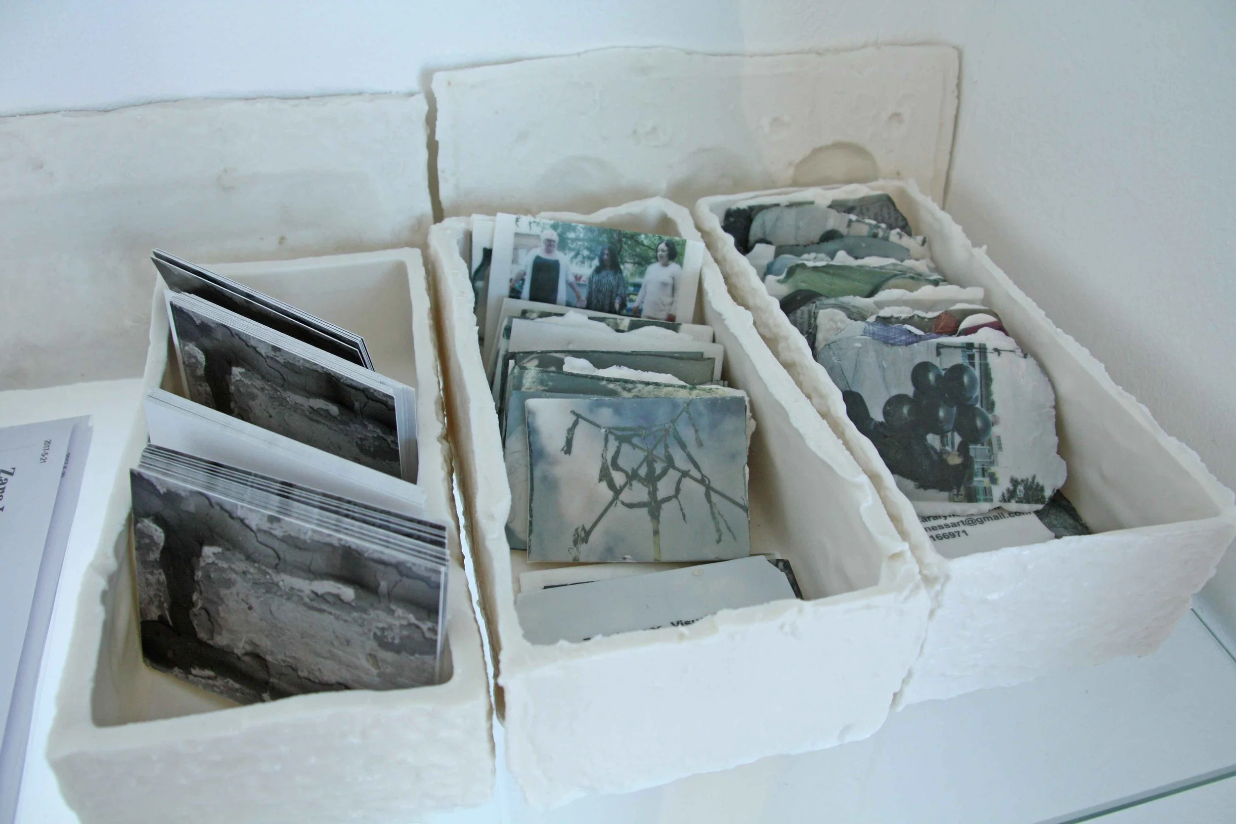 Collection of small photographs and cards stored in white foam trays.