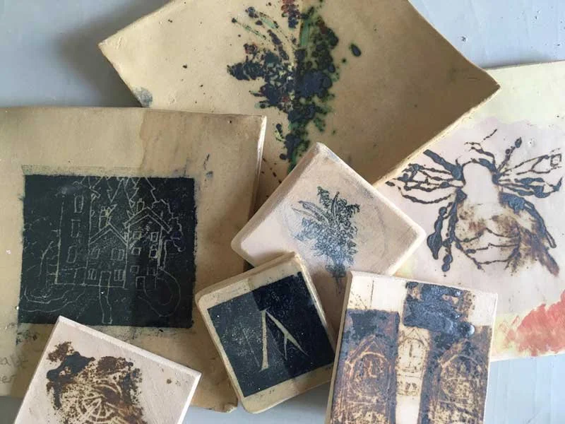 Assorted charcoal or ink prints and sketches on paper, including images of a house, a tree, an insect, and abstract designs.