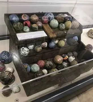 Collection of various colored ceramic balls stored in a black display case.