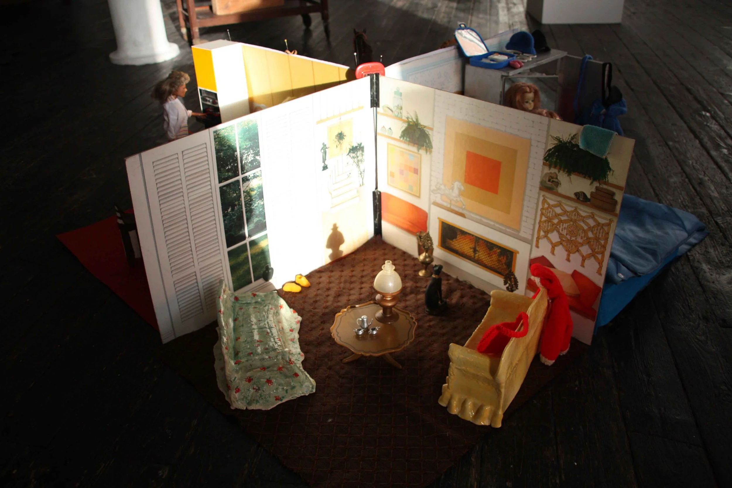 A dollhouse with miniature furniture and decorations, placed on a dark wooden floor.
