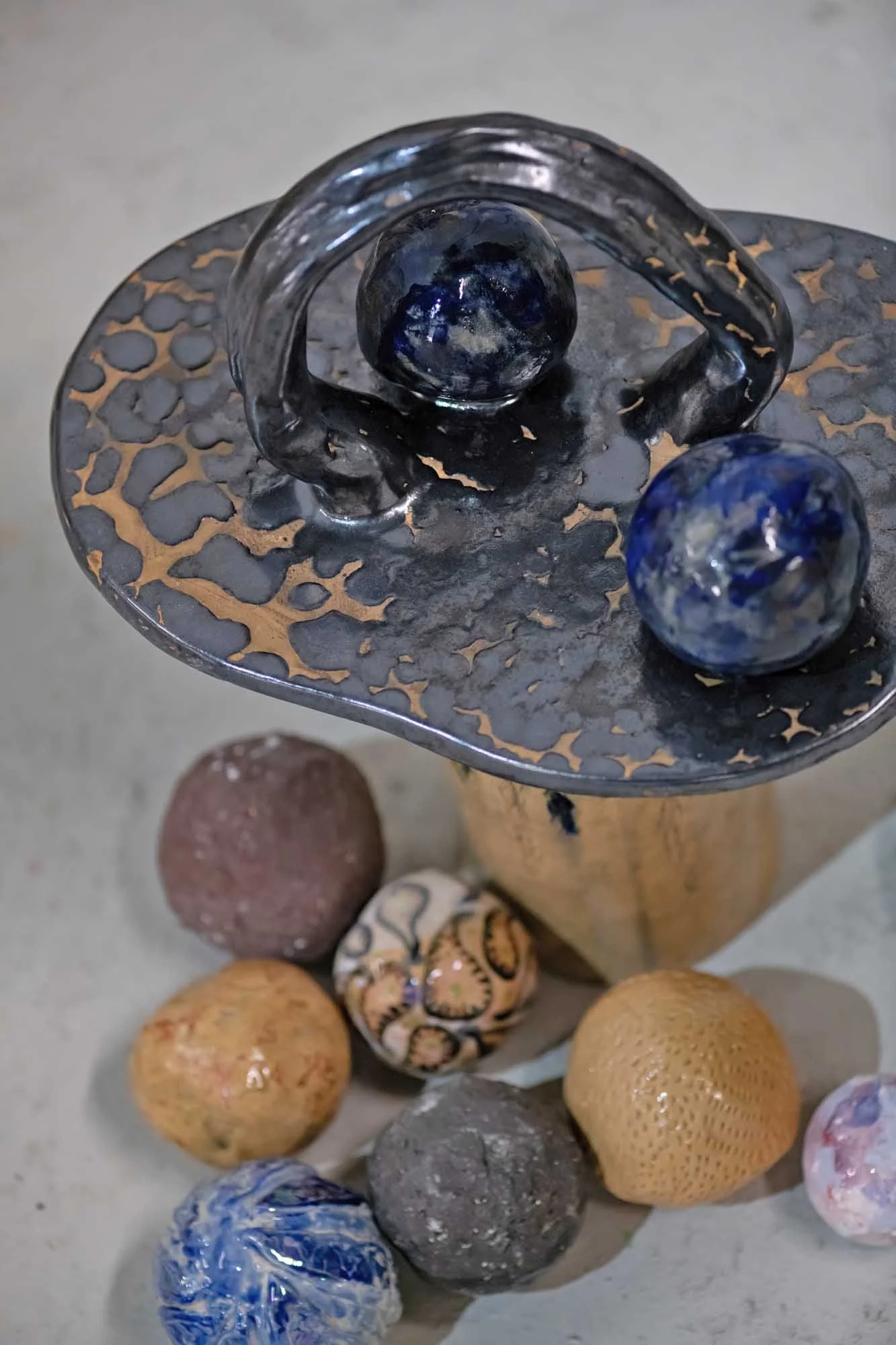 A collection of various textured and colored balls on a surface, with one placed on a ceamic decorative object at the top of the image.