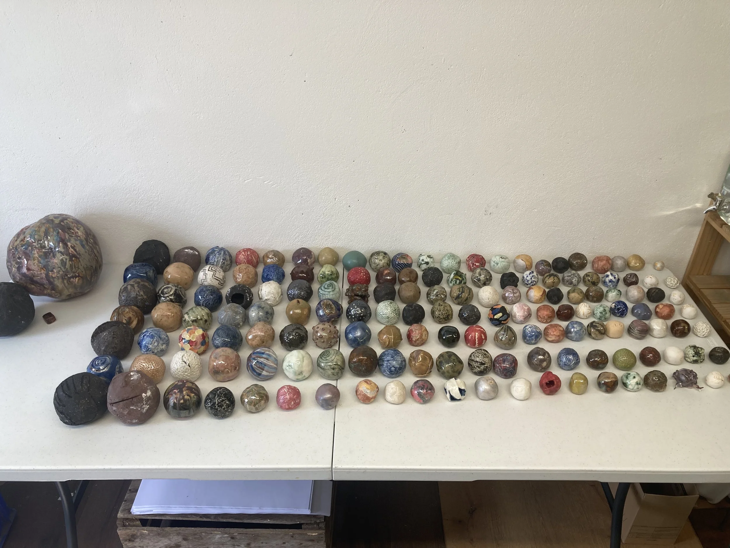 Collection of various polished and unpolished marbles and stones arranged on a white table against a plain wall.