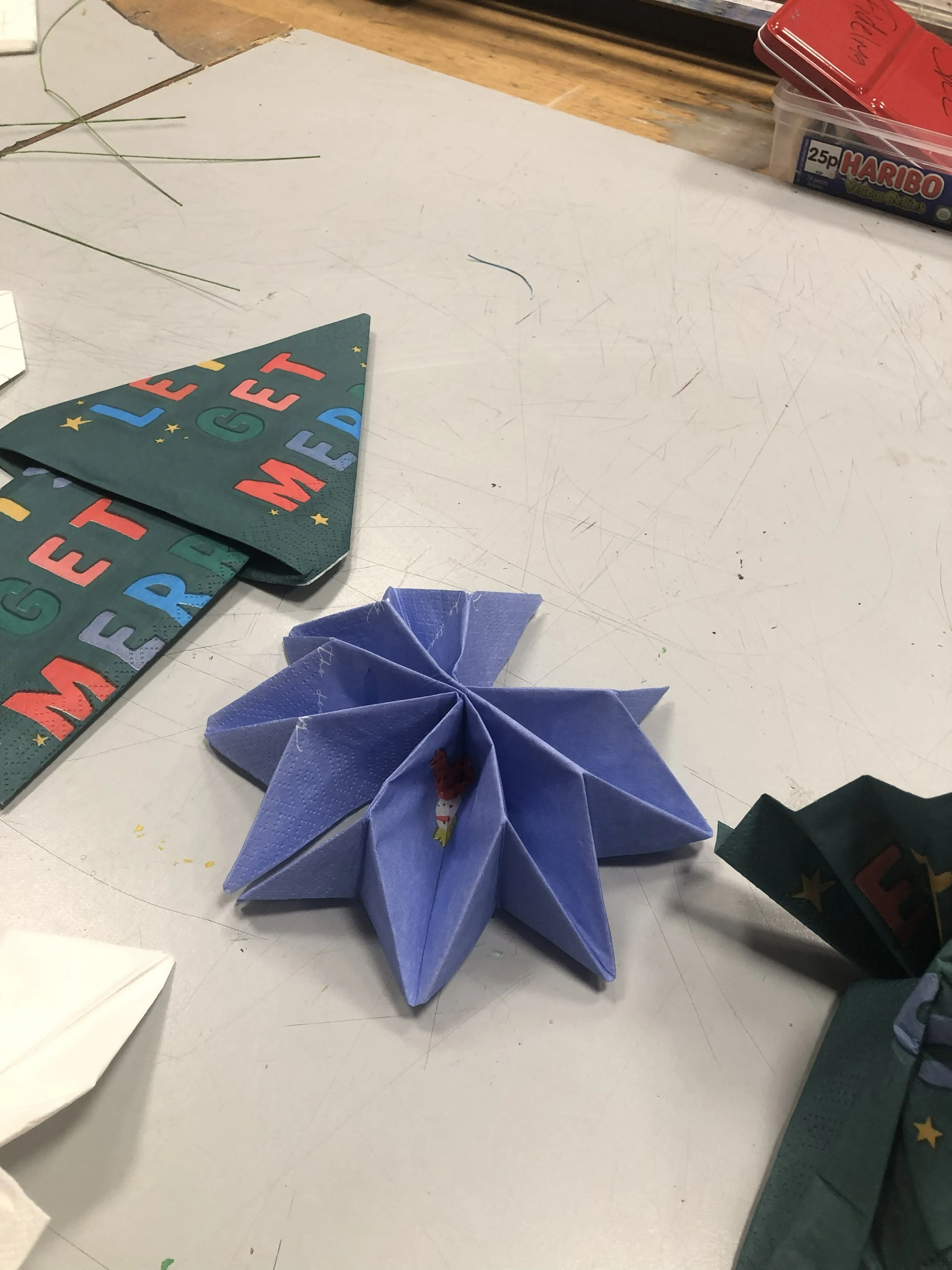 an art workbench with napkins folded in flower, arrow and concertina shapes