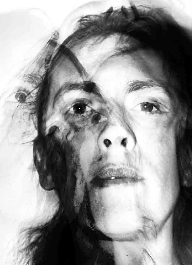 Black and white photo of a woman's face with a double exposure or layered effect creating a distorted and artistic appearance