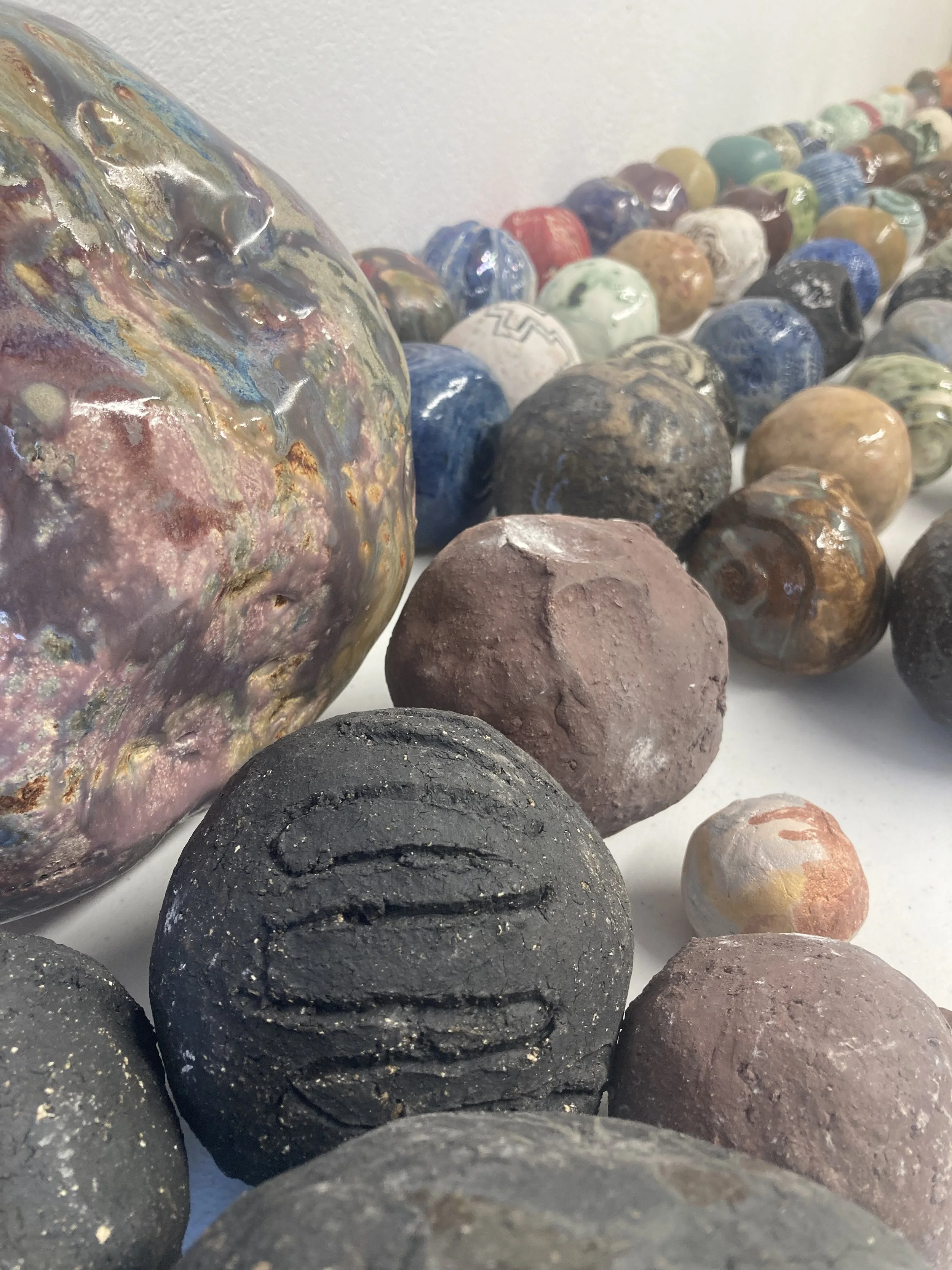 Close-up of various smooth stones and a large iridescent glass object with multicolored patterns.