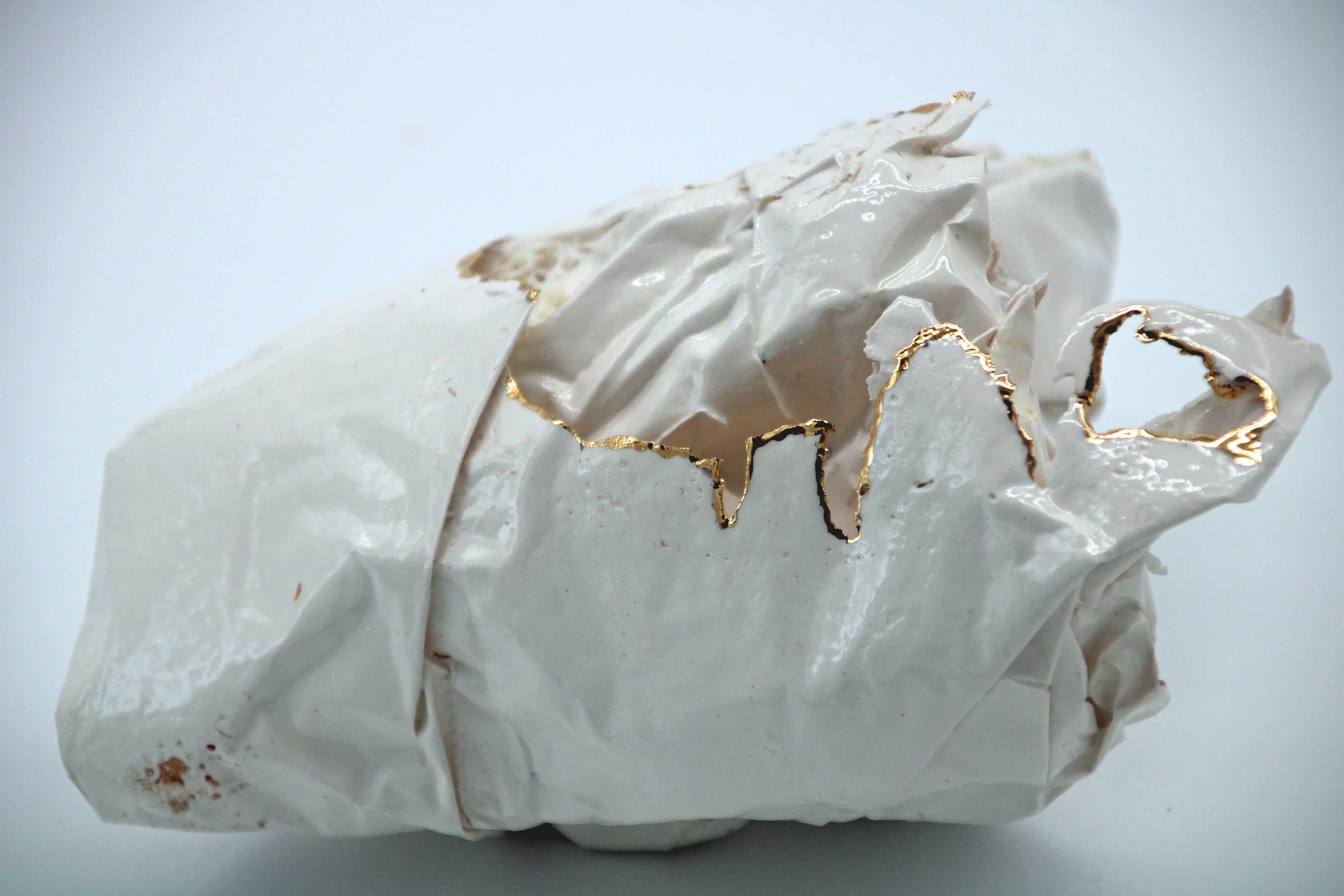 white ceramic piece that looks like scrunched paper with gold on some edges