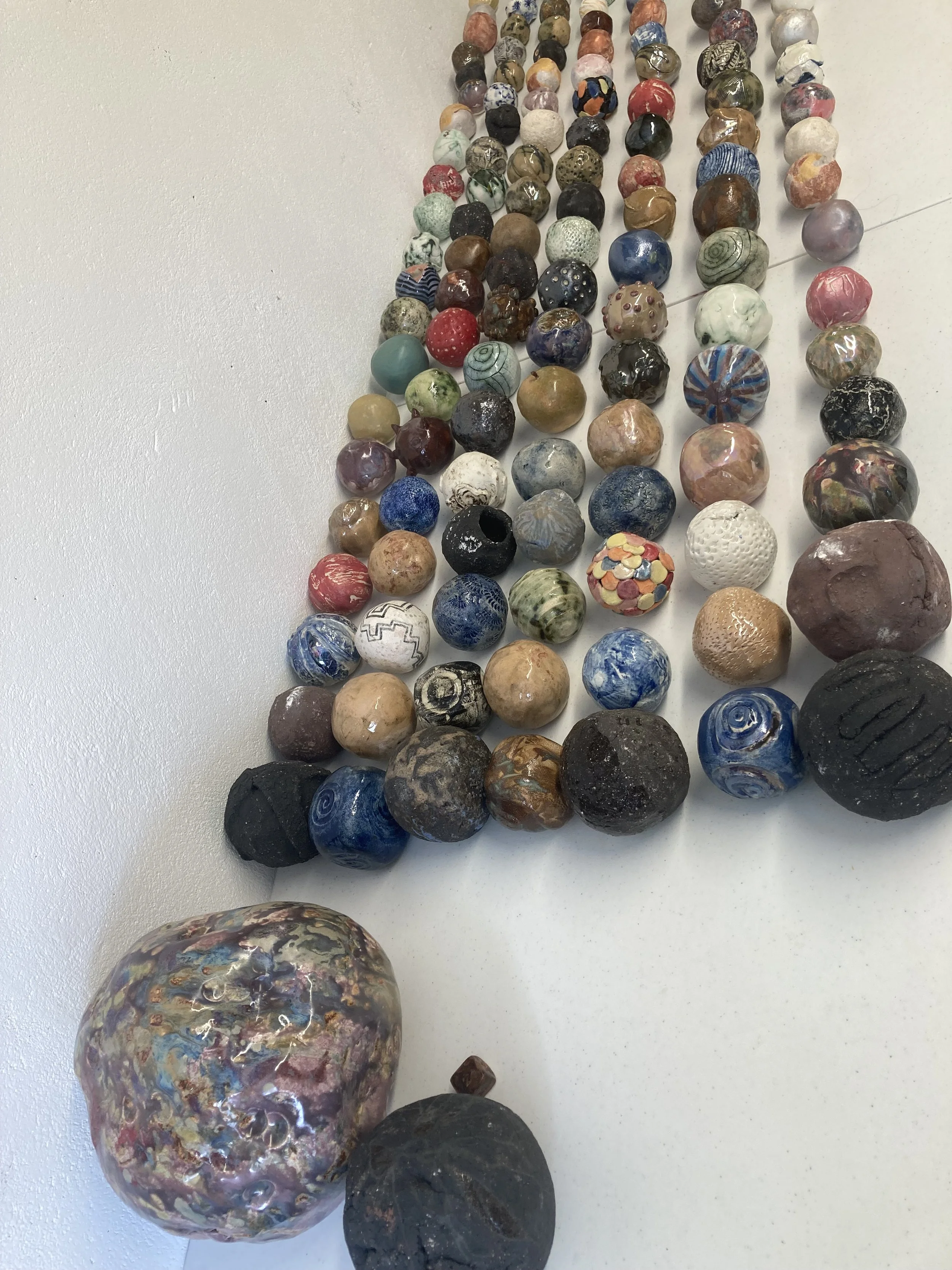 Collection of polished and decorated marbles arranged on a white surface.