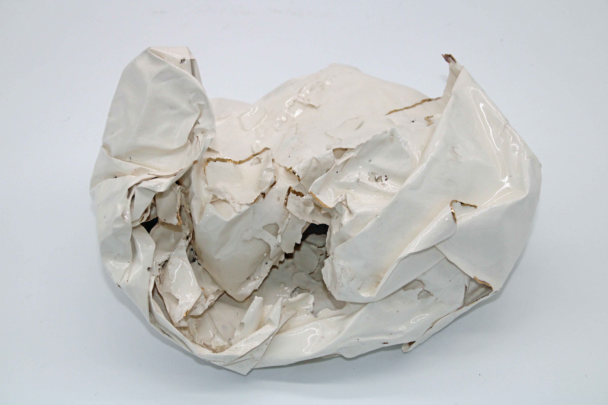 white ceramic piece that looks like scrunched paper with gold on some edges