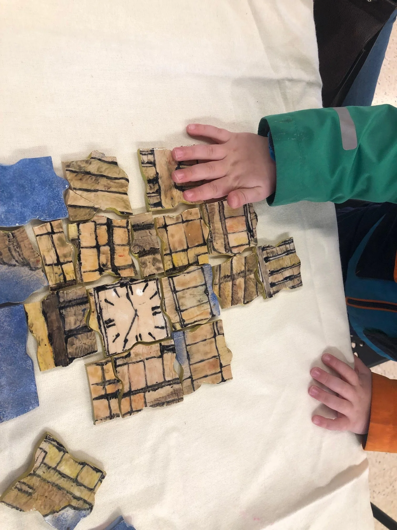 Child's hand touching a series of tiles arranged on a table with various images and patterns.