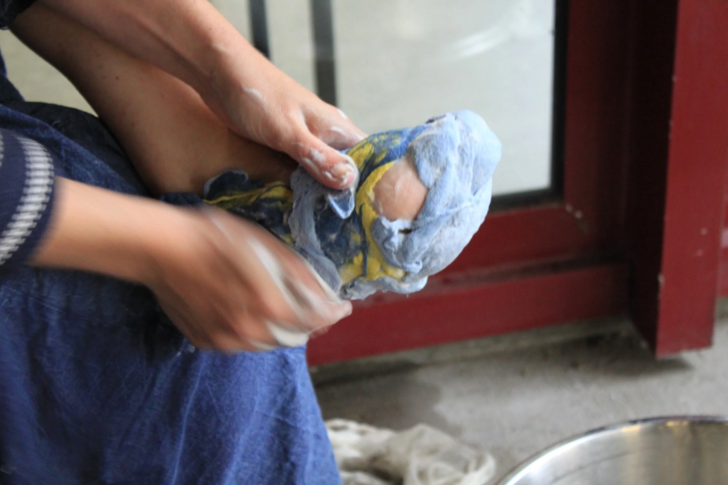 A person holding a crumpled, dirty cloth or rag in their hands. The person's arms and part of their torso are visible, with a focus on their hands.
