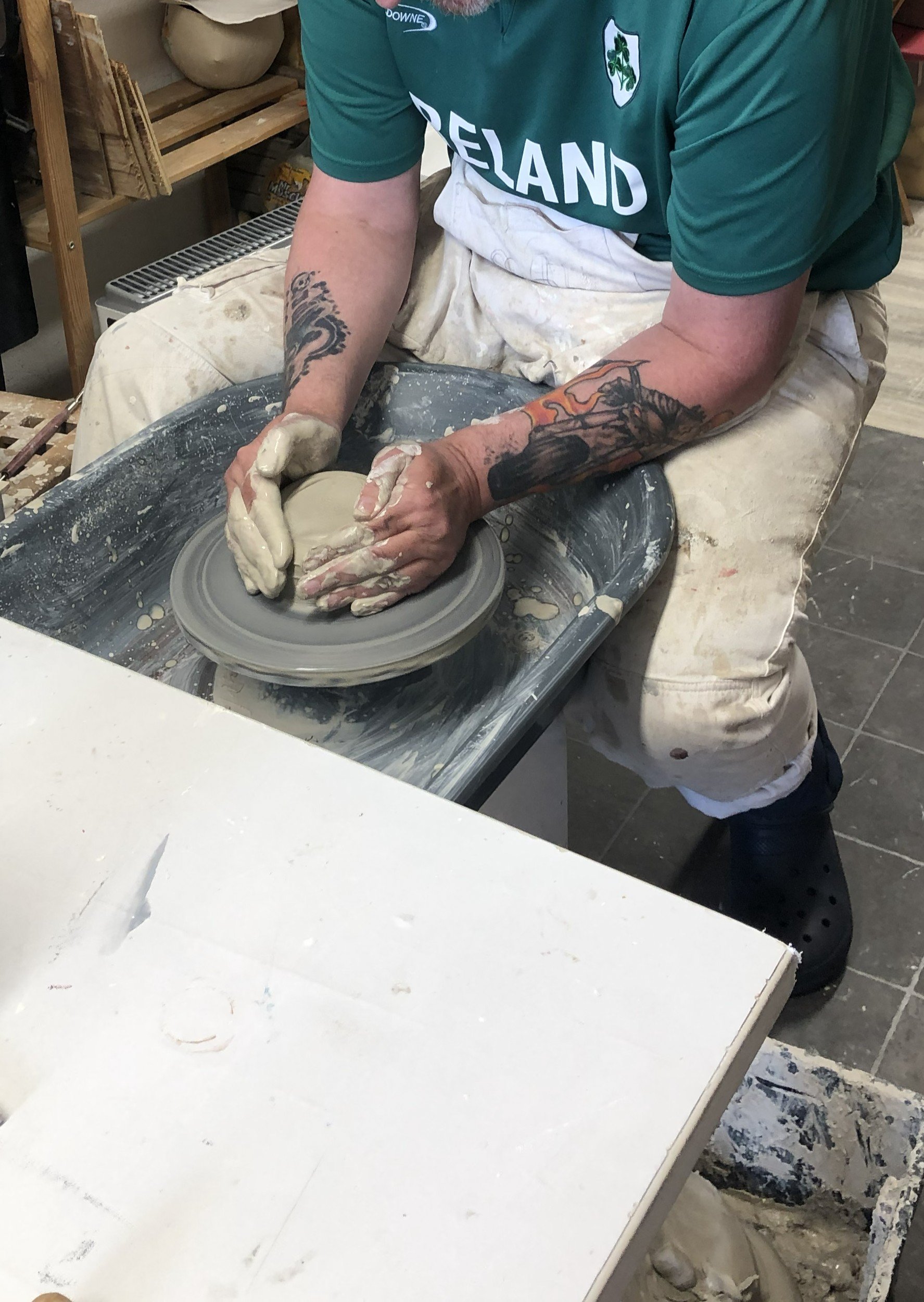 cropped image of a man wearing an ireland rugby shirt throwing on a pottery wheel