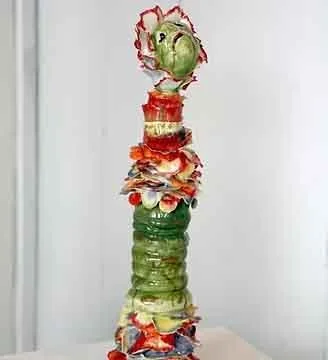 Tall thin ceramic figurine with petals as a neck ruff at the figure head.