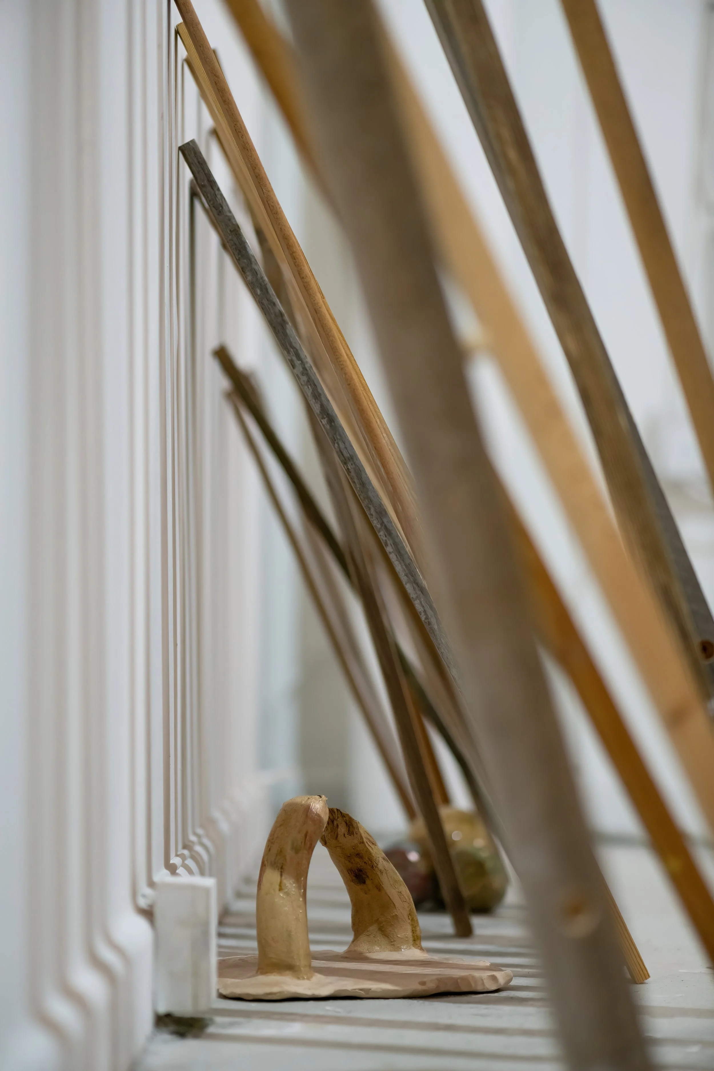A collection wooden posts leaning against a wall with small balls on the floor