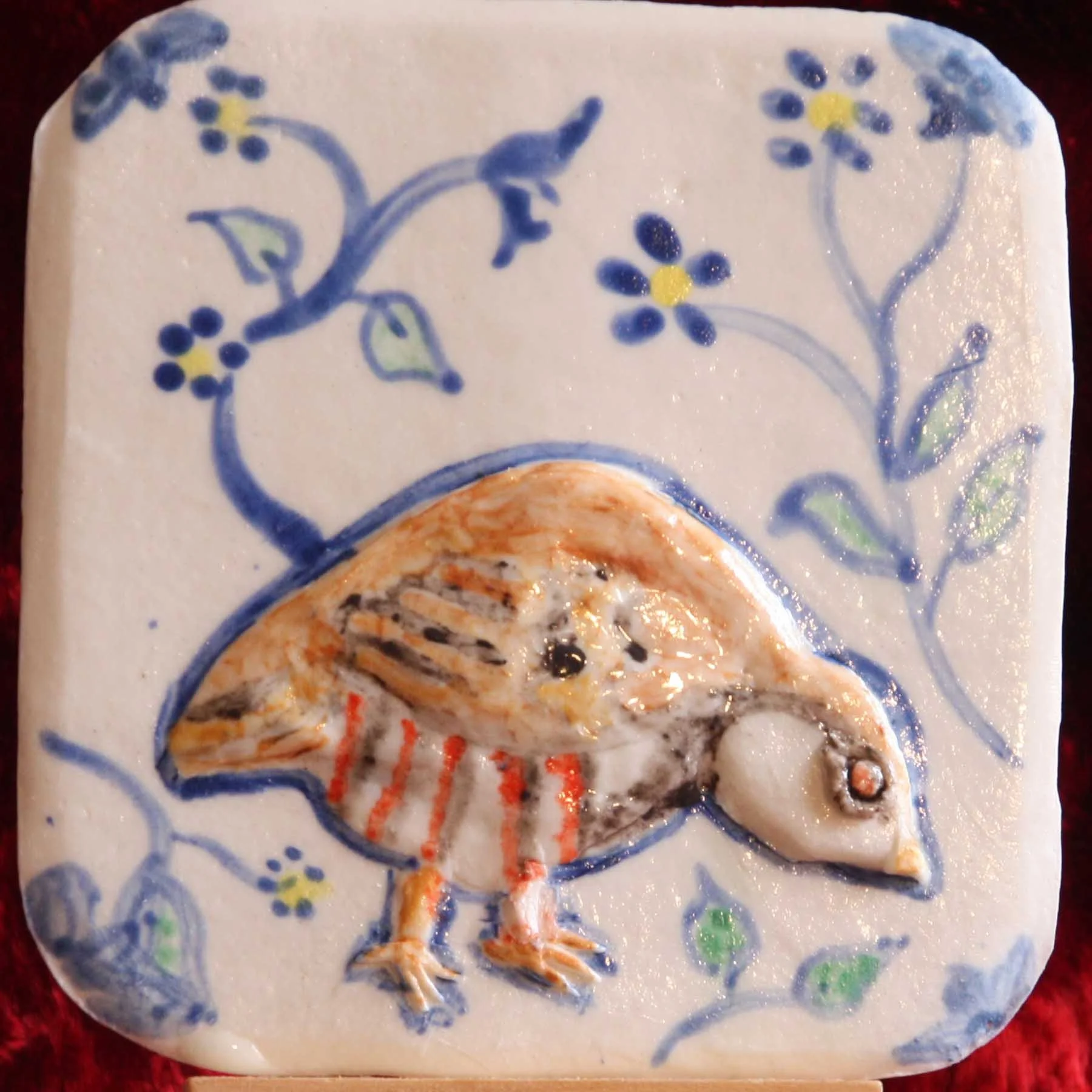 A ceramic plate with a hand-painted floral design in blue and yellow, featuring small flowers and leaves on a white background.