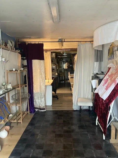 Interior space with shelves, curtains, tables, and various household items.