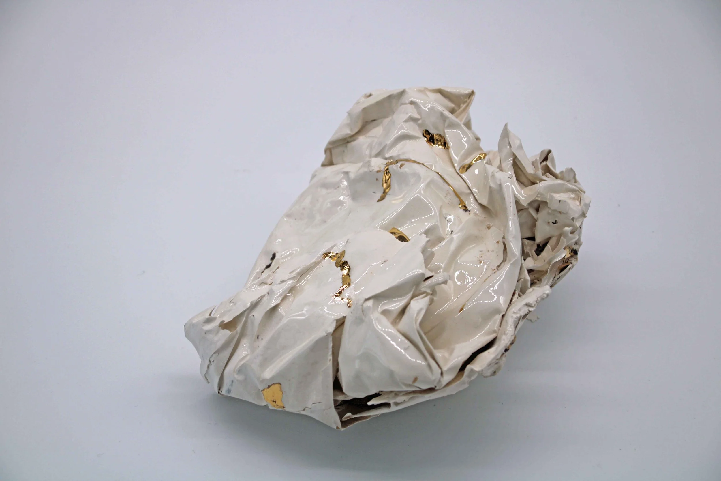 white ceramic piece that looks like scrunched paper with gold on some edges