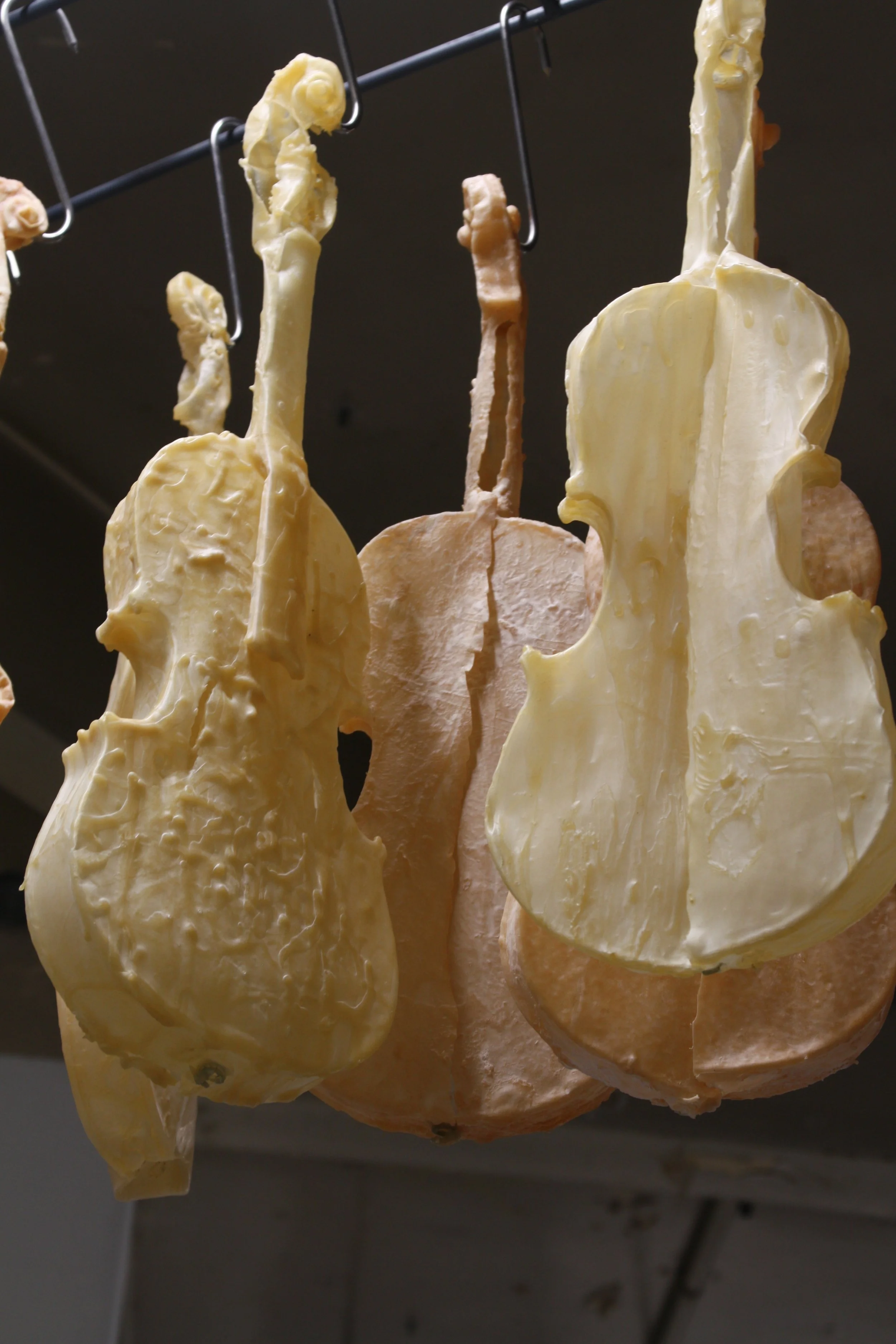 Latex violin  hanging from hooks on a metal rack.