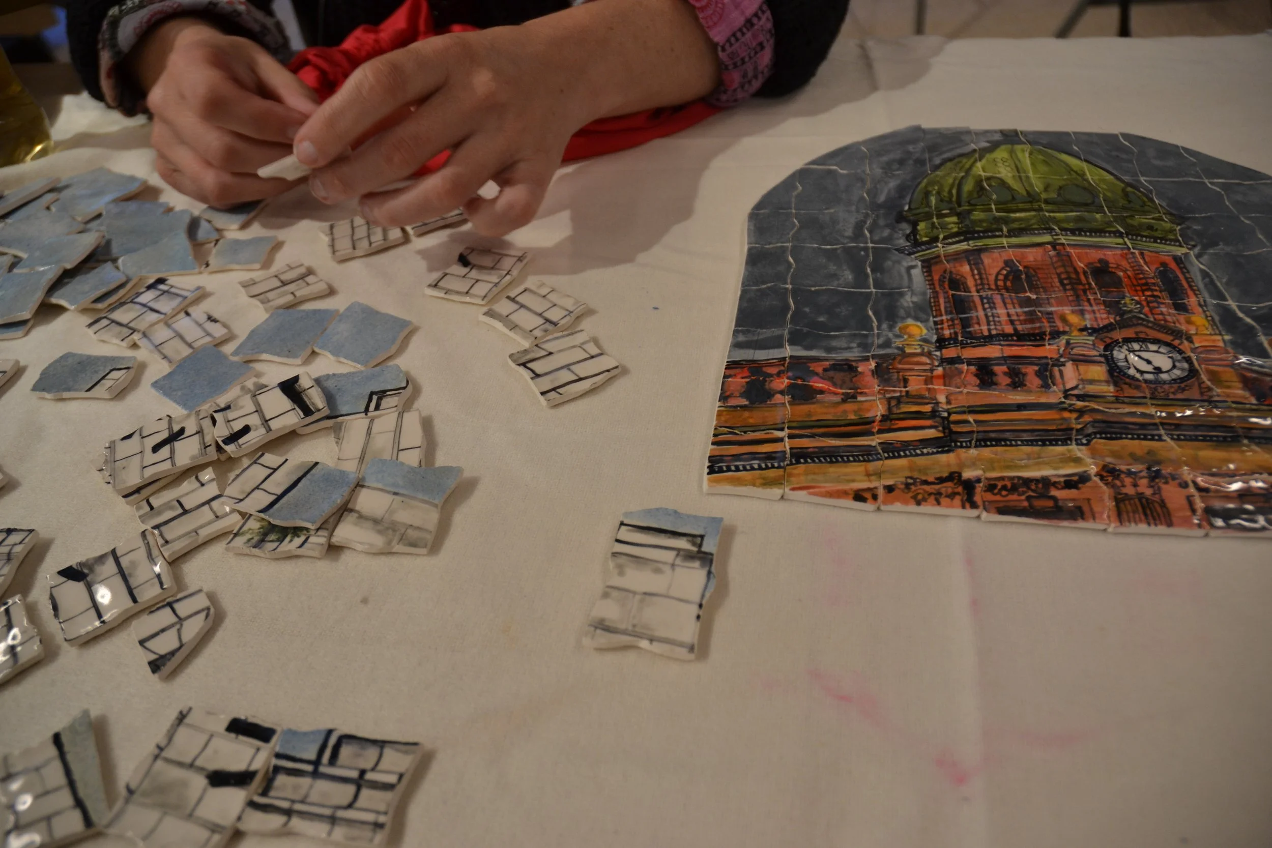 Person assembling a jigsaw puzzle depicting a building with a clock tower.