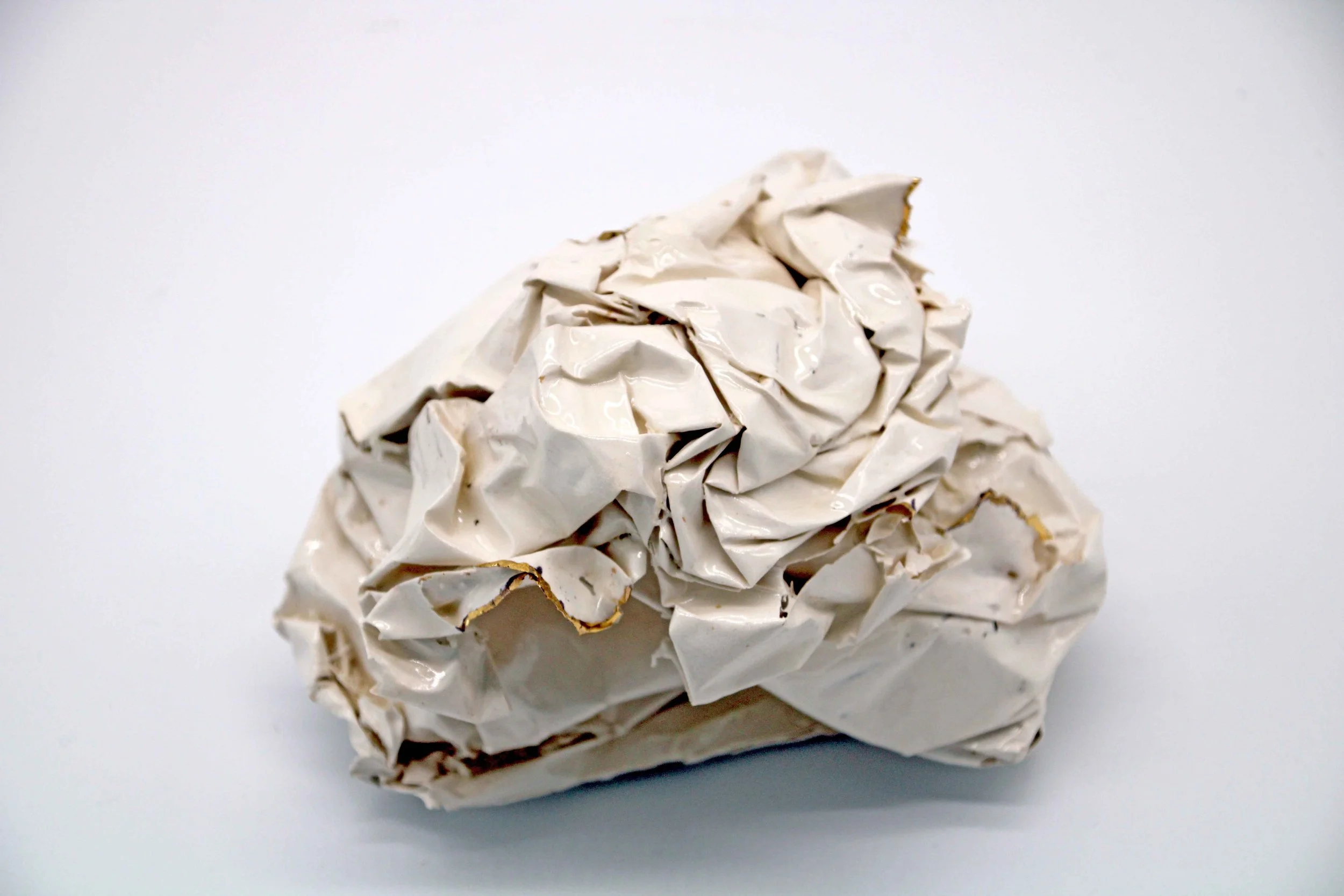 white ceramic piece that looks like scrunched paper with gold on some edges