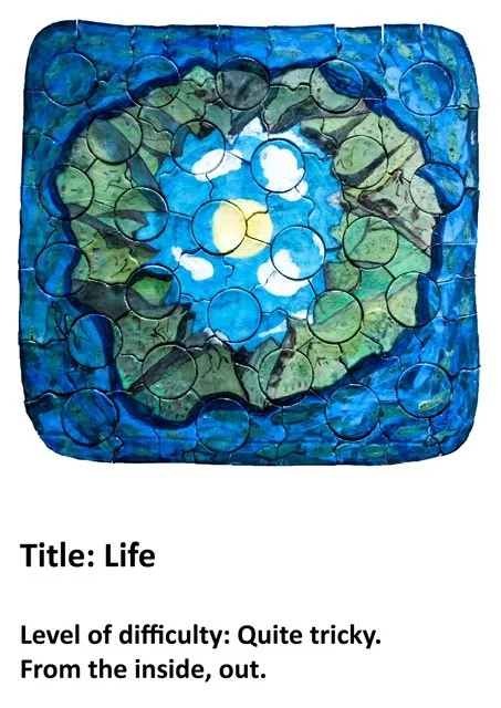 A colorful jigsaw puzzle depicting a heart-shaped design with a cross inside. The puzzle features shades of blue, green, and yellow, with the heart and cross prominently centered.