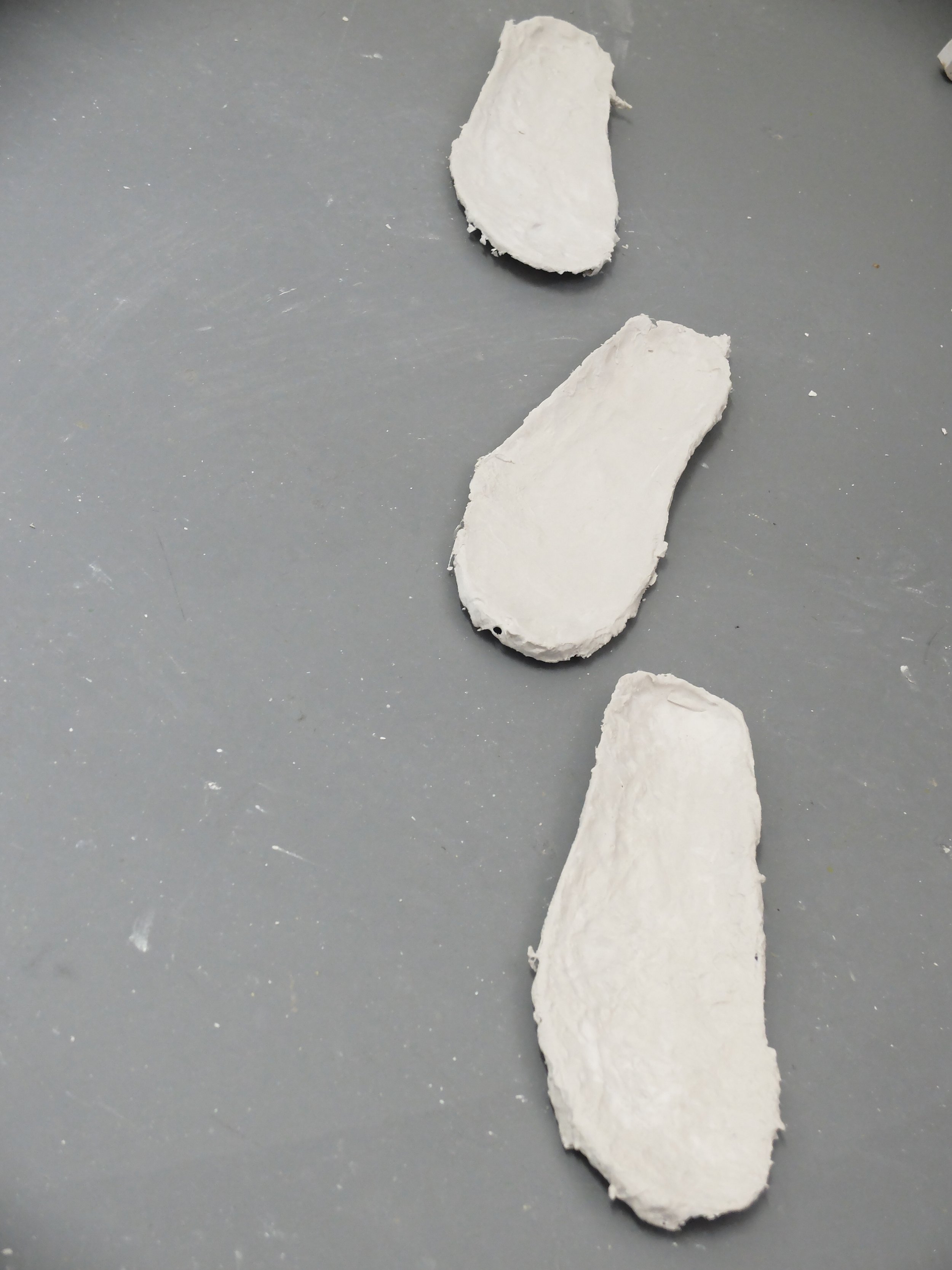 Uncooked pieces of white drywall or plasterboard on a gray surface.