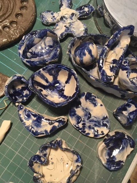 Ceramic shards with blue and white glaze on a crafting table.