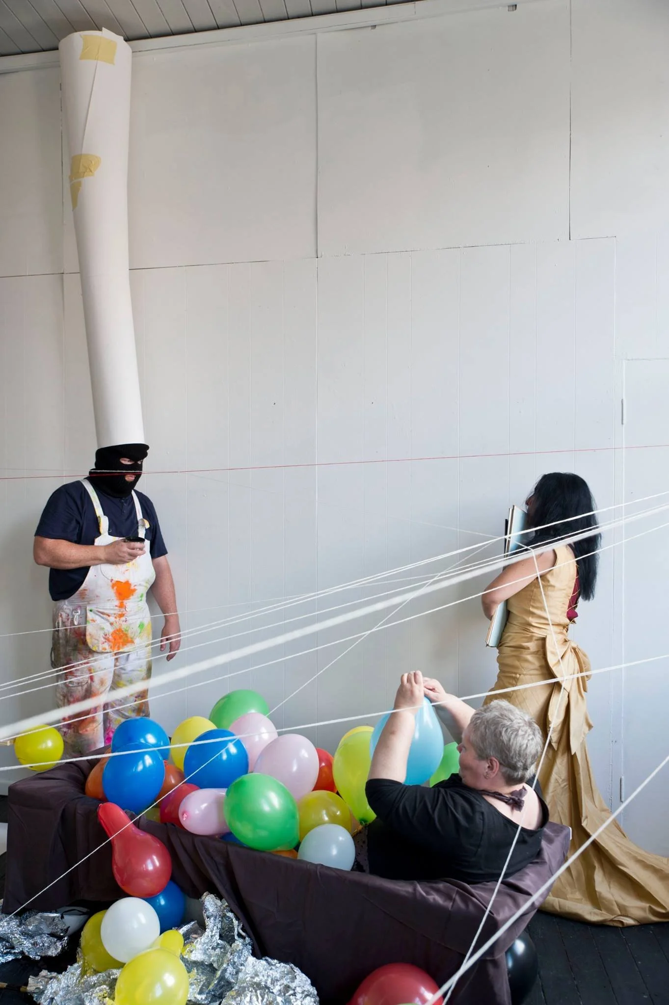 People celebrating with balloons, some sitting in a large box and others standing next to it inside a building.