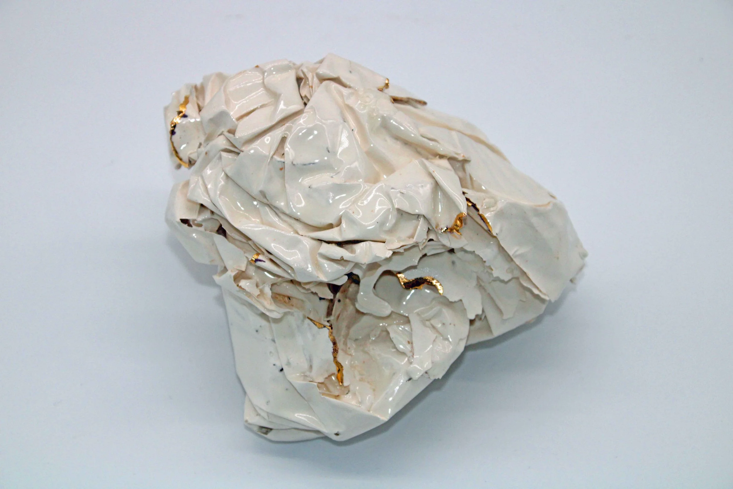 white ceramic piece that looks like scrunched paper with gold on some edges