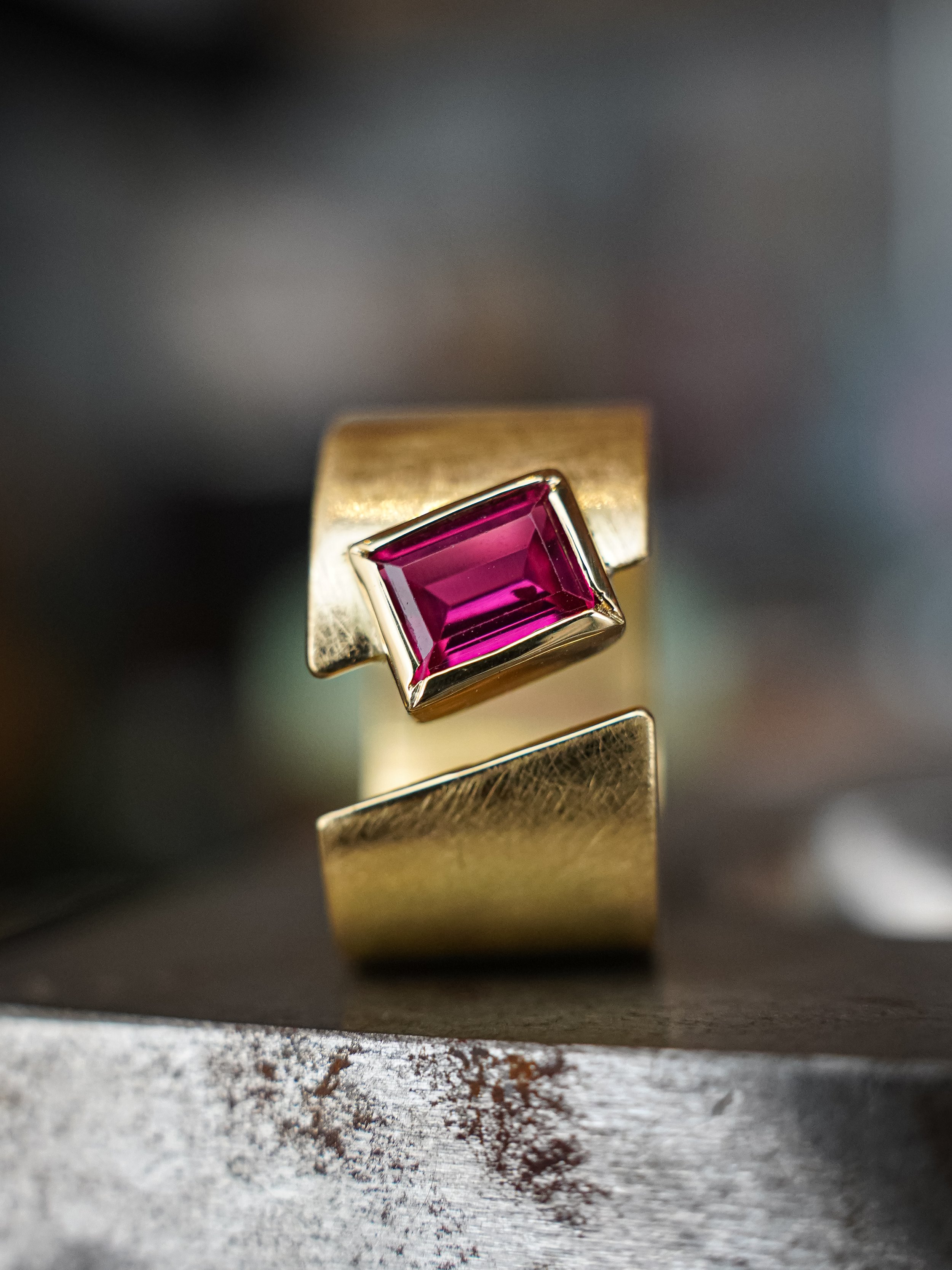 Anillo de oro con una piedra preciosa rosa en forma cuadrada.
