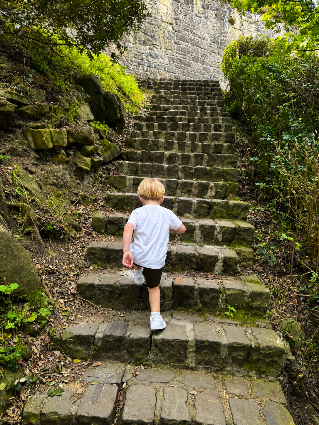 Child climbing mossy stone steps at Monte Urgull in San Sebastián, Spain