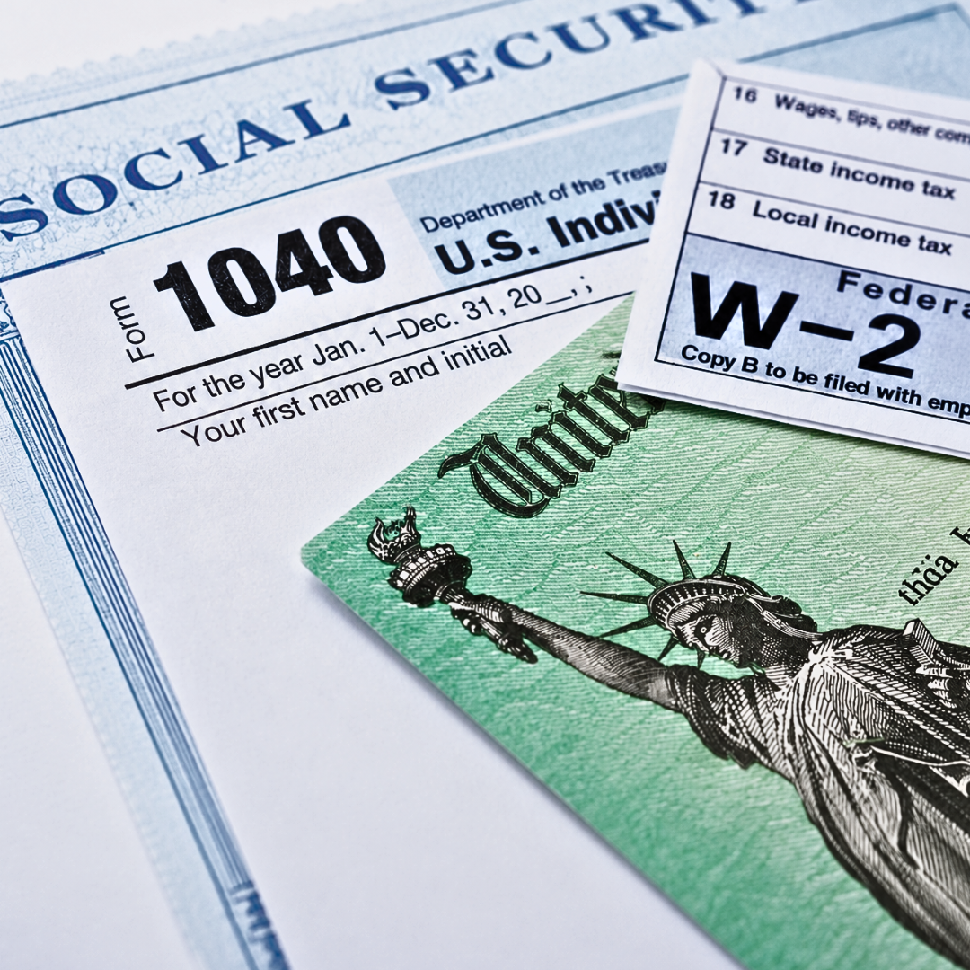 Close-up of a social security card, a tax document, and a check with the Statue of Liberty on it.