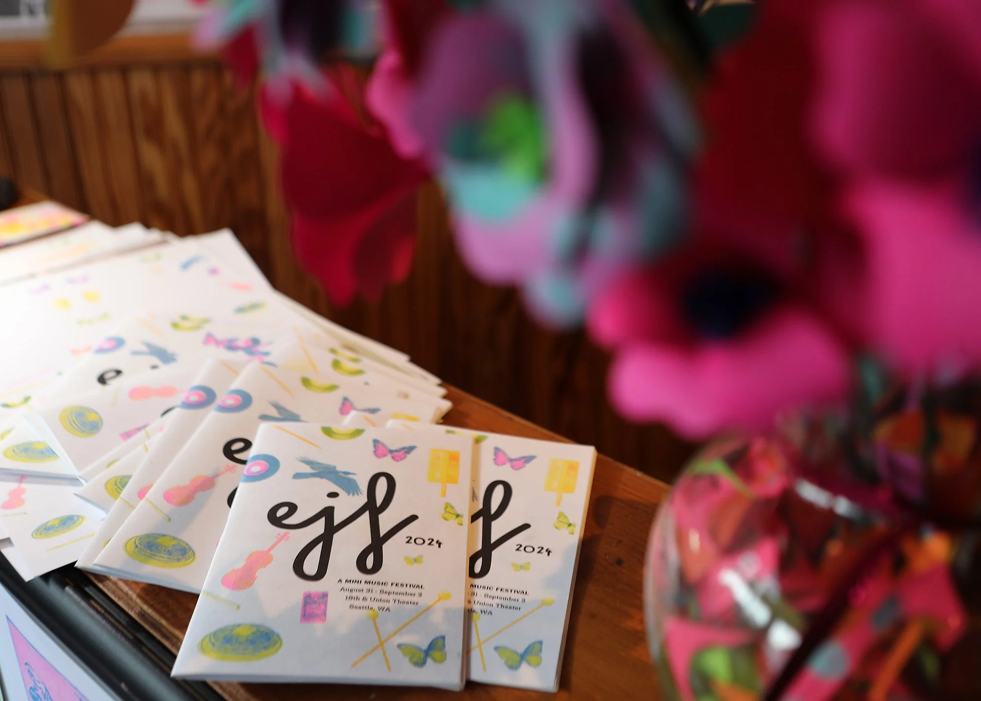 A stack of colorful program booklets for a music festival, titled 'EJF Fest 2024,' displayed on a wooden table.