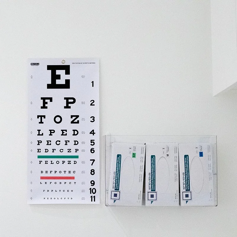 Eye chart and three eye exam appointment cards on a white wall.