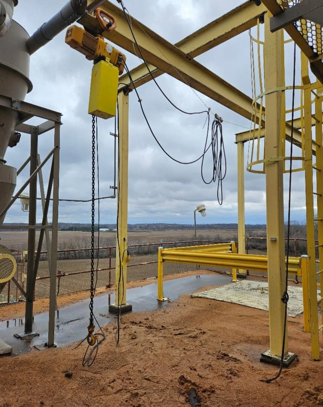 Industrial playground with yellow metal structures, wires, and a cloudy sky in the background.