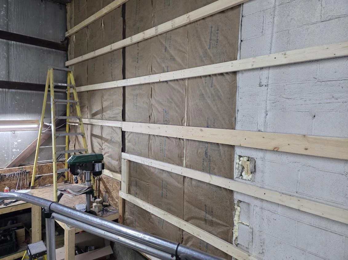 Construction site with wooden framing on wall, ladder, and tools