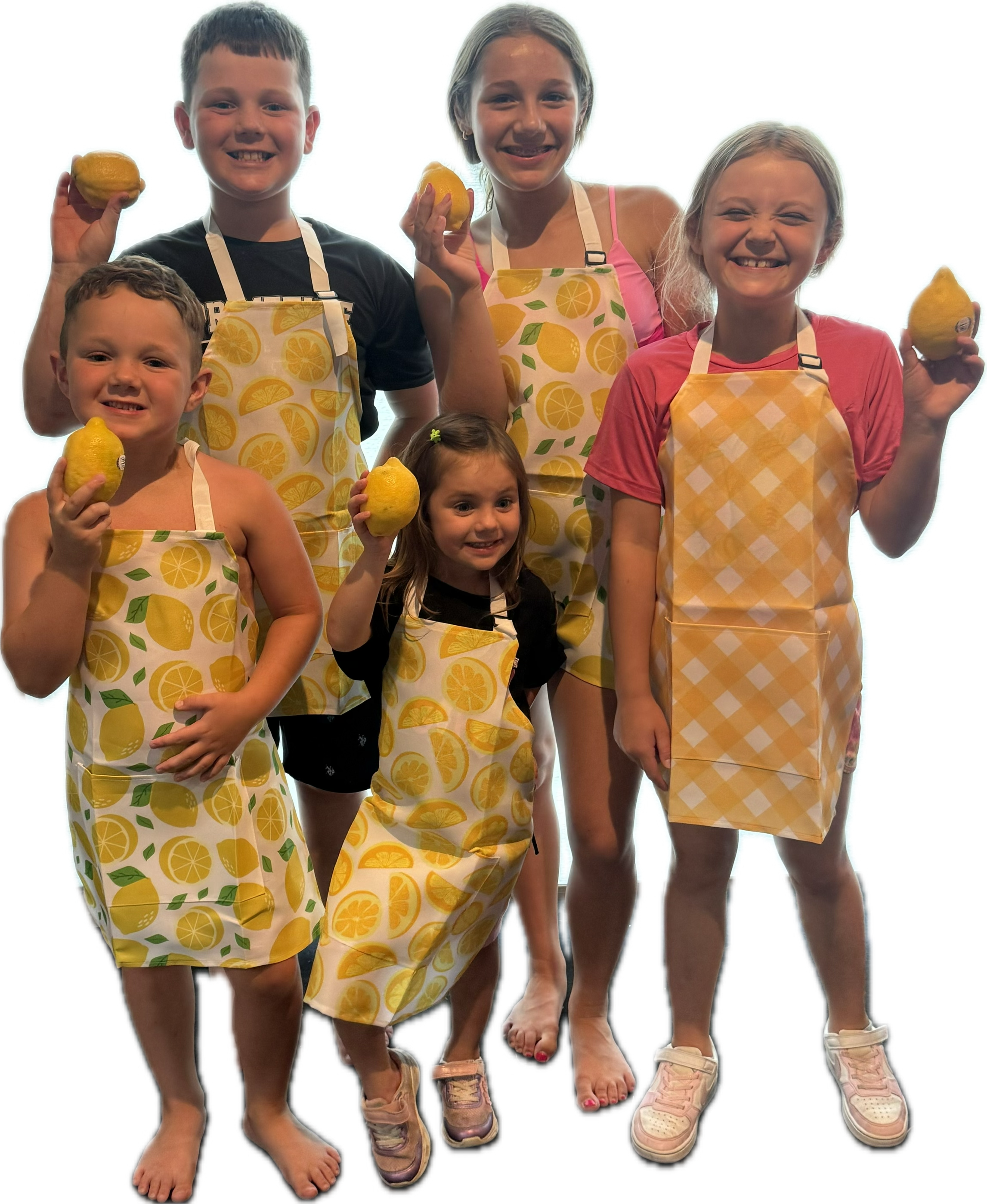 Group of five children standing together, holding yellow lemons, wearing aprons with lemon patterns, and smiling.
