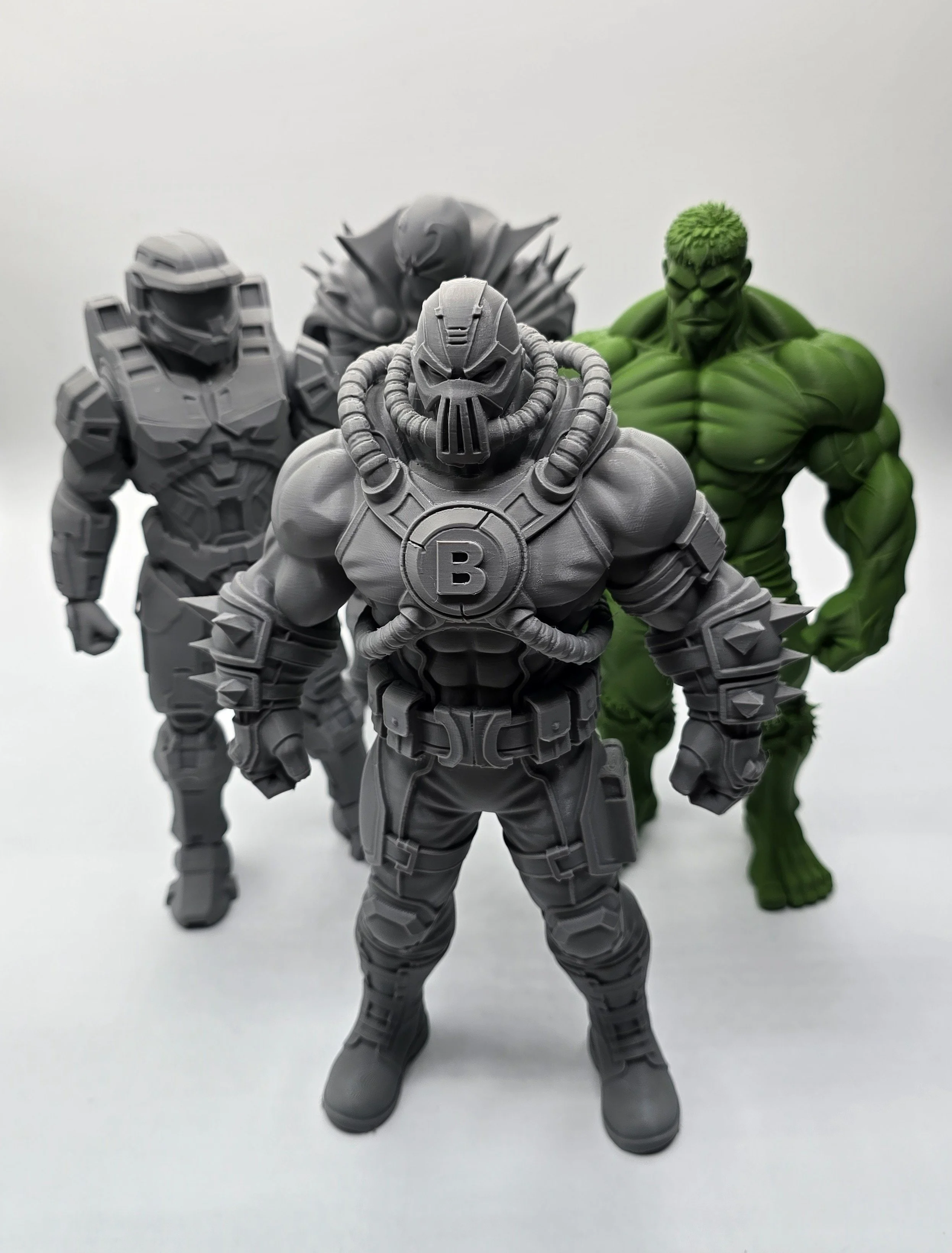 Four action figures of fictional characters, with a mixture of gray and green colors, standing on a white background.
