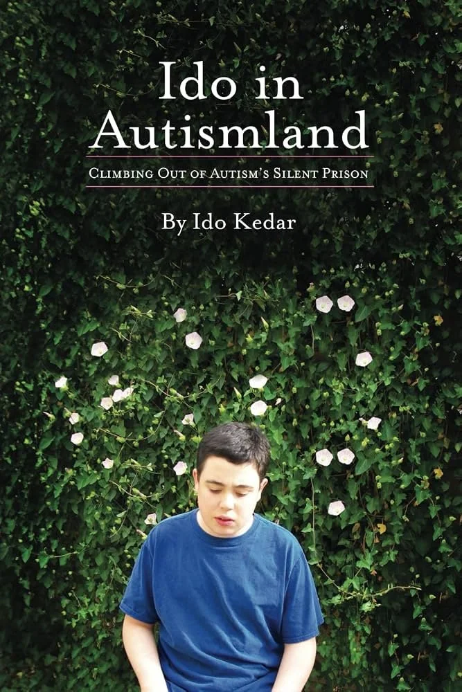 Book cover titled "I Do in Autismland" with subtitle "Climbing Out of Autism's Silent Prison" by Ido Kedar, featuring a young boy in a blue shirt looking down, standing in front of green leafy bushes with white flowers.
