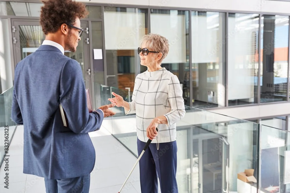 A blind woman talking to a male colleague