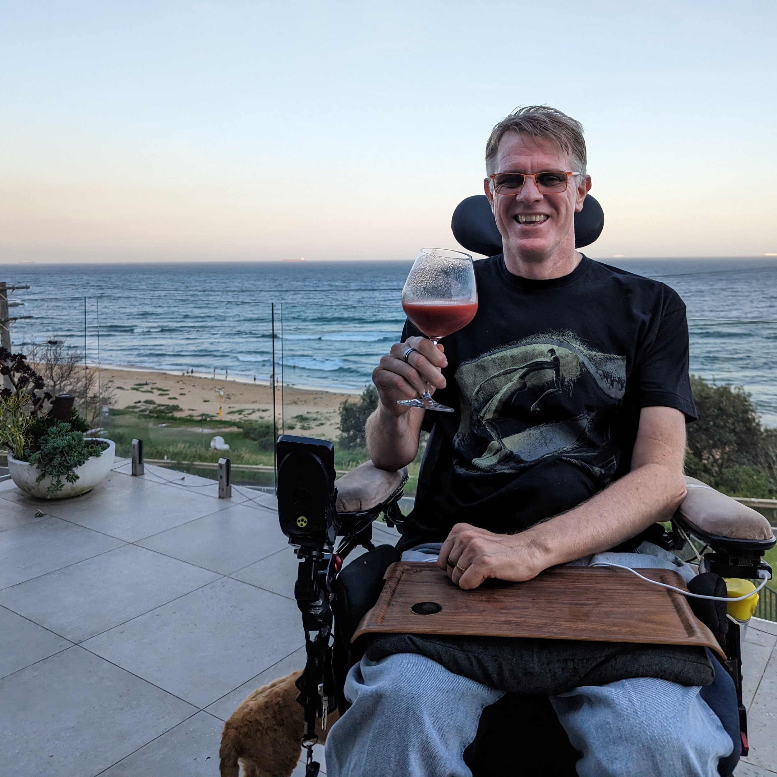 Shane Clifton in a wheelchair enjoying a drink before a beach