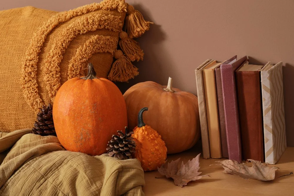 Reading bench with fall decor including pillow, throw blankets, pumpkins and books.