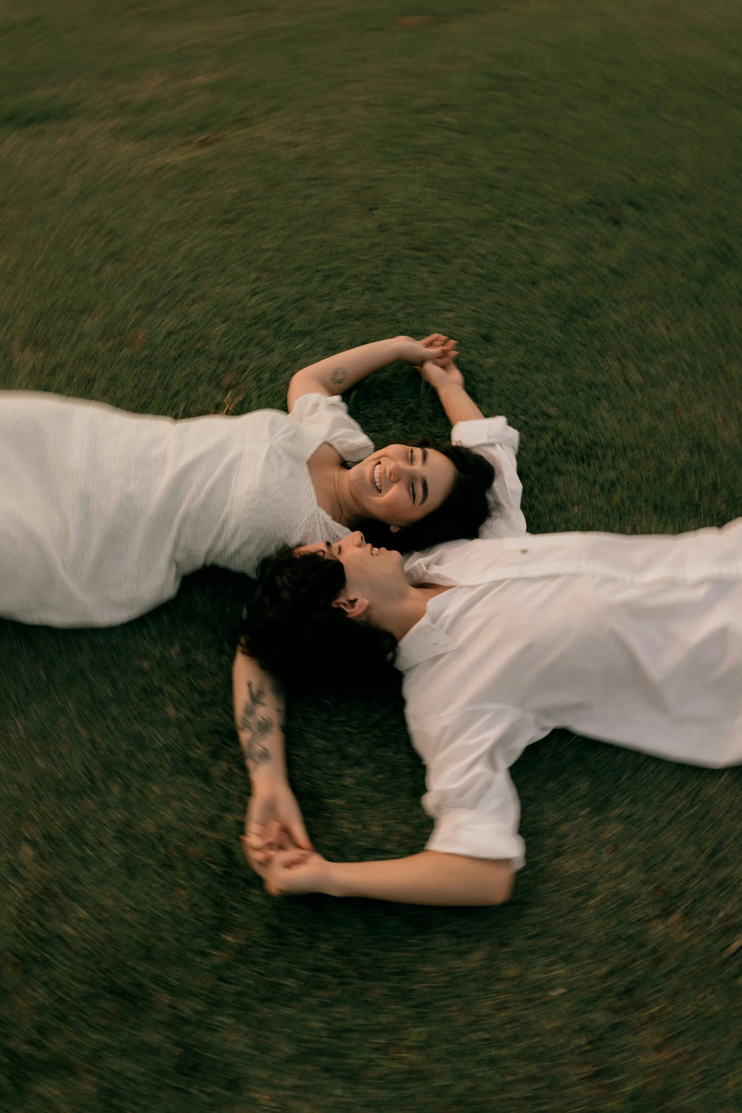 a couple laying on a grassy field