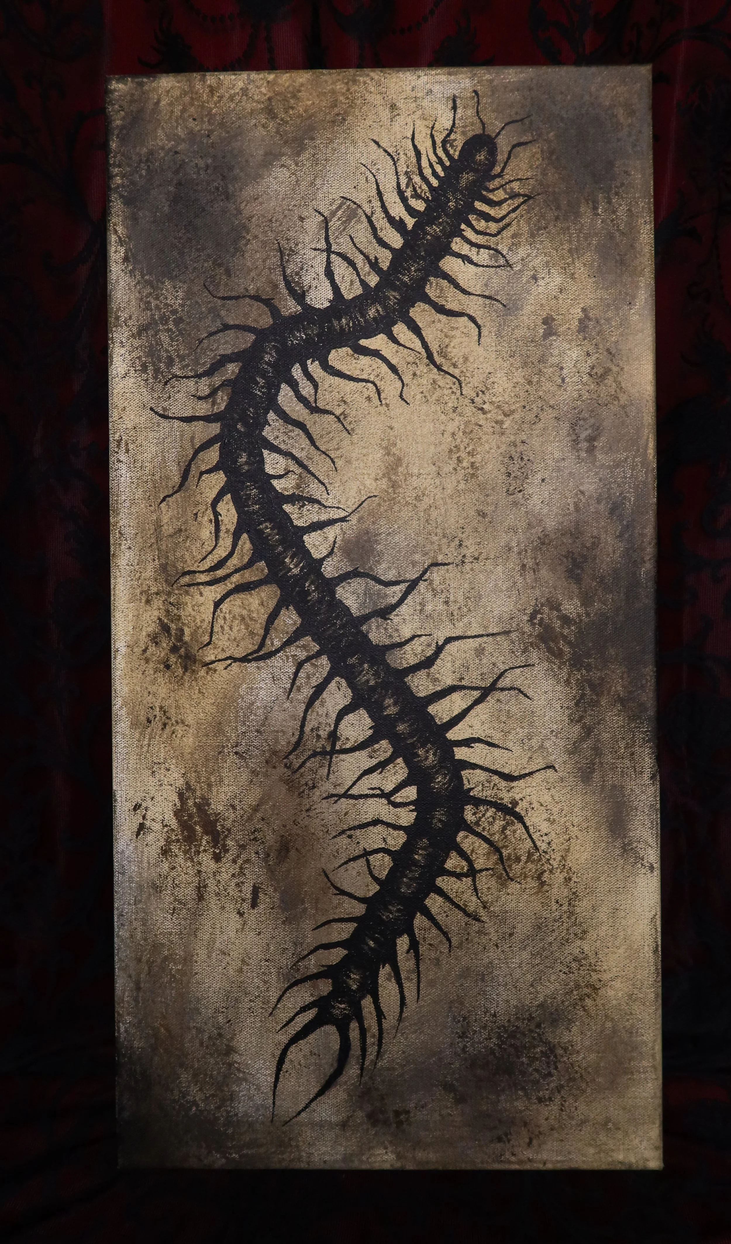 A painting of a black centipede with a textured brown and beige background.