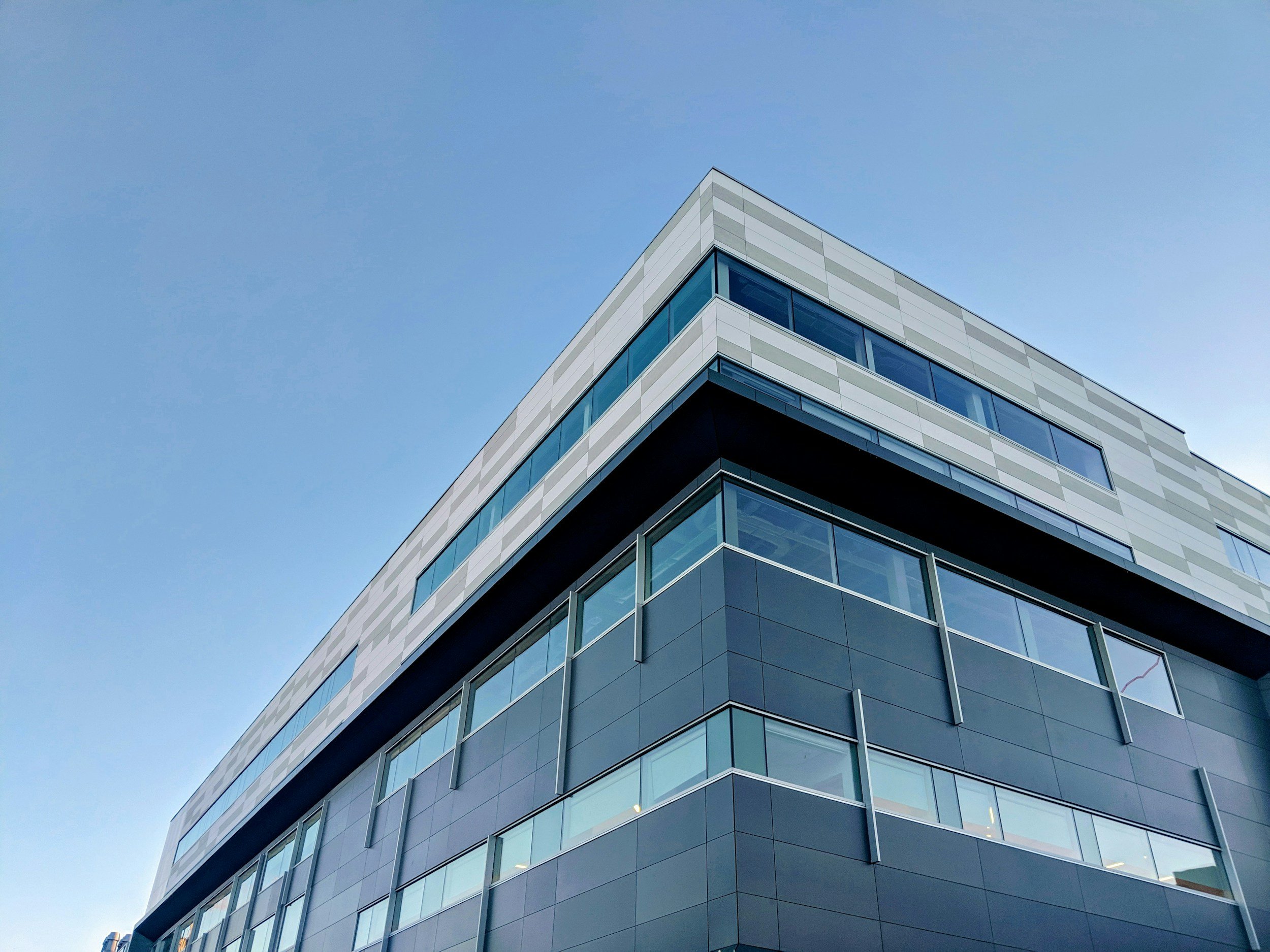A modern multi-story building with a glass exterior against a clear blue sky.